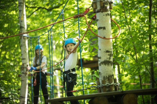 Aventura de cuerdas en el bosque una niña y su madre se divierten en el puente de cuerdas