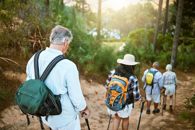 Aventura de caminhada e exploração com um grupo de amigos seniores caminhando em uma trilha na floresta ou floresta retrovisor de aposentados fazendo uma caminhada ou viagem em férias de descoberta ao ar livre