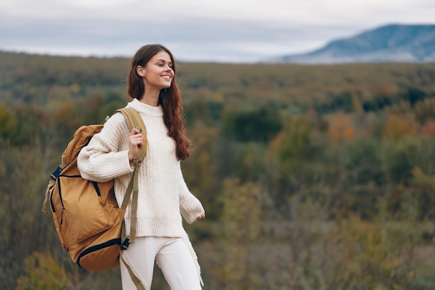 Aventura de montanha mulher sorridente de mochila no penhasco desfrutando de caminhadas de primavera