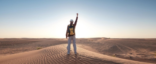 Aventura en el desierto Joven con mochila caminando sobre una duna de arena de Dubai, Emiratos Árabes Unidos