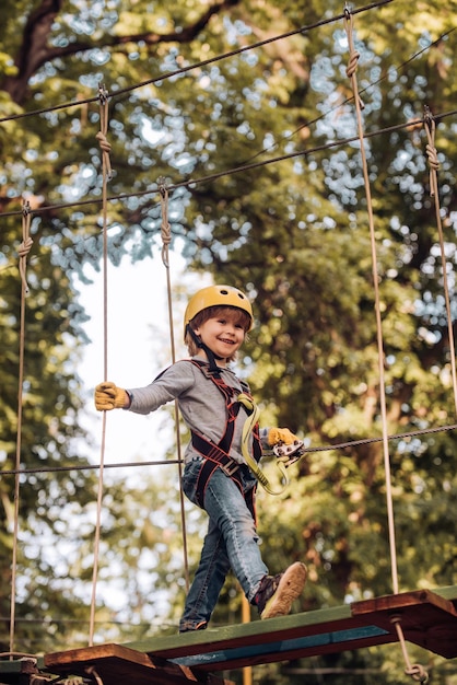 Aventura escalando parque de alambre alto Niño Niño lindo niño Las obras de arte representan juegos en un complejo ecológico que incluye zorro volador o red de araña Niño trepando árboles en el parque