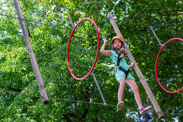 Aventura escalando parque de arame - pessoas em curso em capacete de montanha e equipamentos de segurança