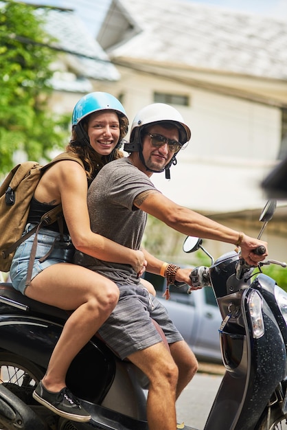 Aventura espera Retrato de dois mochileiros felizes andando de moto por uma cidade estrangeira