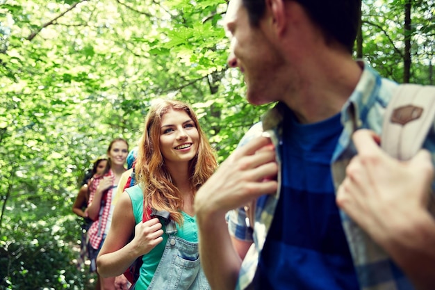 aventura, viagens, turismo, caminhada e conceito de pessoas - grupo de amigos sorridentes andando com mochilas na floresta