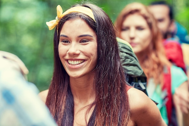 aventura, viagens, turismo, caminhada e conceito de pessoas - grupo de amigos sorridentes andando com mochilas na floresta