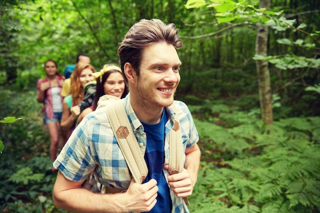 aventura, viagens, turismo, caminhada e conceito de pessoas - grupo de amigos sorridentes andando com mochilas na floresta