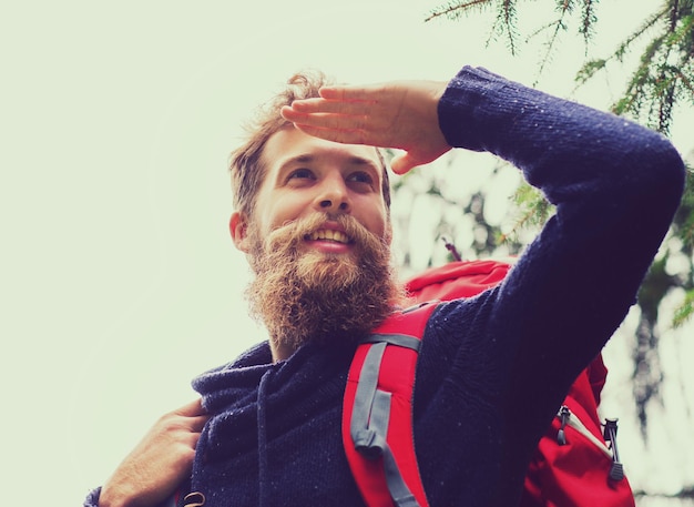 aventura, viagens, turismo, caminhada e conceito de pessoas - homem sorridente com barba e mochila vermelha caminhadas