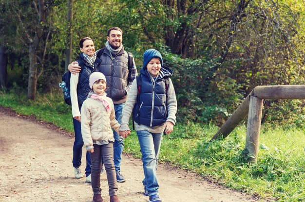 aventura, viajes, turismo, caminata y concepto de personas - familia feliz caminando con mochilas en el bosque