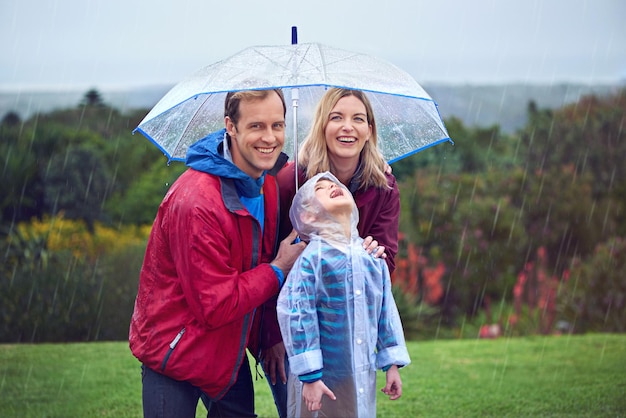 Aventuras de dia chuvoso Retrato recortado de uma família de três do lado de fora na chuva