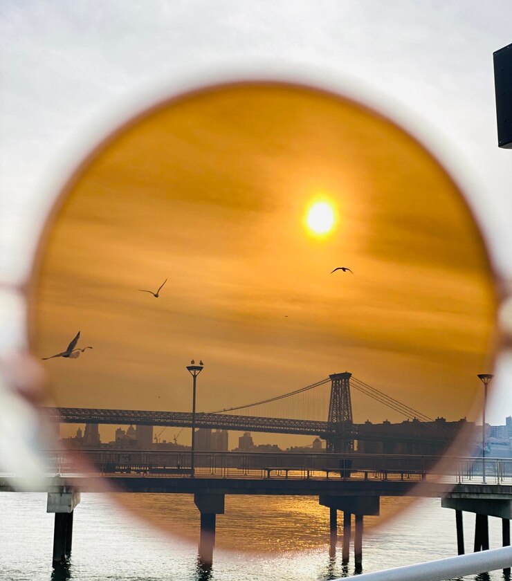 Foto aves volando sobre el puente y el mar durante la puesta de sol vistas a través de gafas de sol
