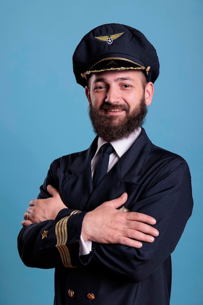 Aviador de aviones de pie en un retrato uniforme profesional, capitán de avión confiado de pie, mirando a la cámara, plano medio del estudio, vista lateral. Piloto civil con insignia en la chaqueta