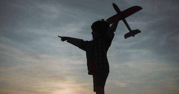 Aviador infantil com avião sonha em viajar no verão na natureza ao pôr do sol menino com avião no hidromel