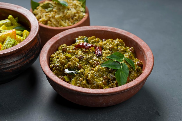 AvialKootu Curry and Cabbage FryKerala traditionelle Beilagen, die sehr gesunde und schmackhafte vegetarische Gerichte sind, die in einem Steingut mit grauem Hintergrund angeordnet sind