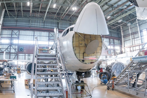 Avião a jato branco de passageiros em manutenção no hangar de aviação