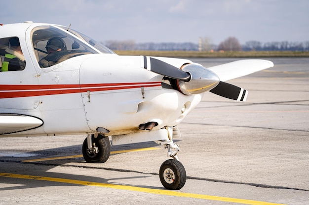 Avião a jato branco frontal em pé na estrada larga.