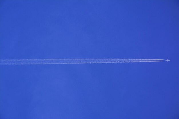 Foto avião com rastro de vapor no céu azul