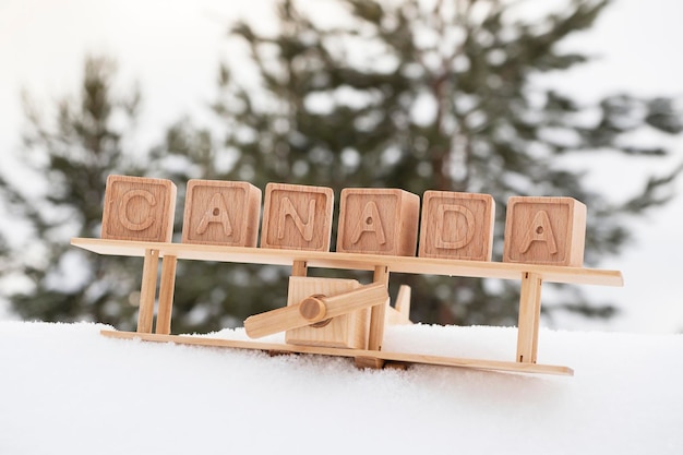 Avião de brinquedo de madeira e a inscrição canadá feito de cubos de madeira no fundo de uma floresta nevada o conceito de viajar para países de inverno para o canadá estilo retro vintage