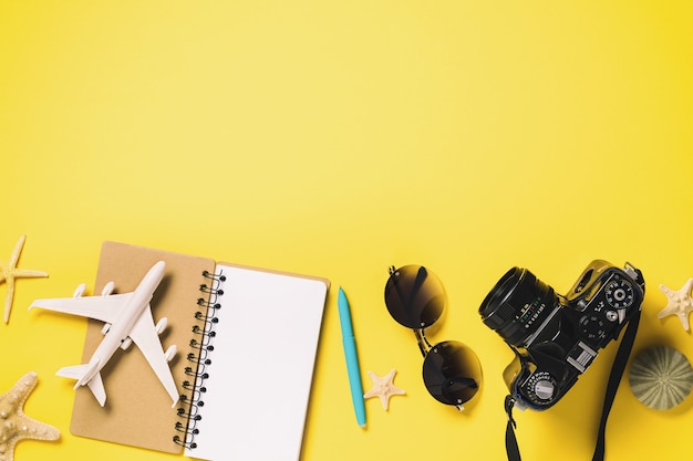 Avião de brinquedo em um notebook com óculos e uma câmera em um fundo amarelo com espaço de cópia