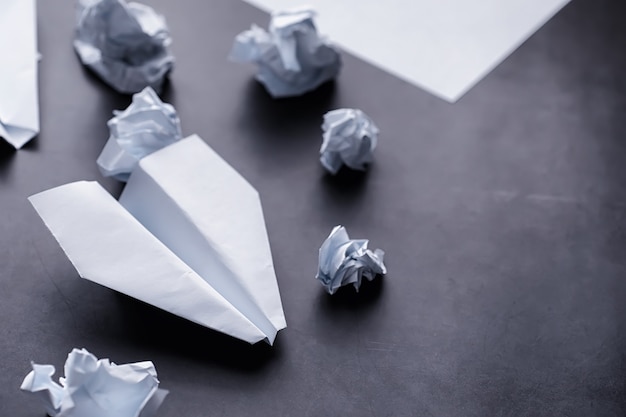 Avião de papel em cima da mesa. Modelo de origami em um fundo escuro. Conceito. Perda de tempo criativa.