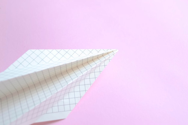 Avião de papel feito de papel em uma gaiola em um fundo rosa