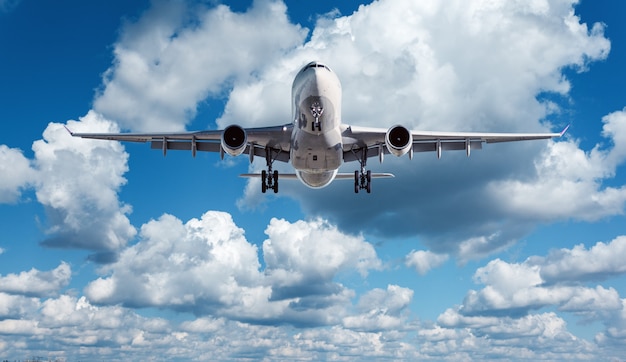 Avião de passageiro branco está voando no céu azul com nuvens