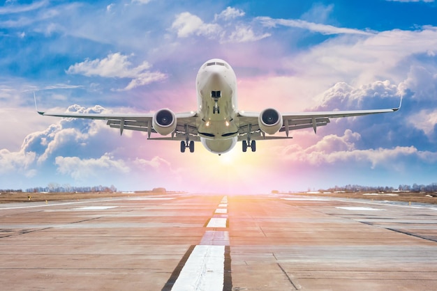 Avião de passageiros branco decola da pista do aeroporto tendo como pano de fundo um céu noturno panorâmico