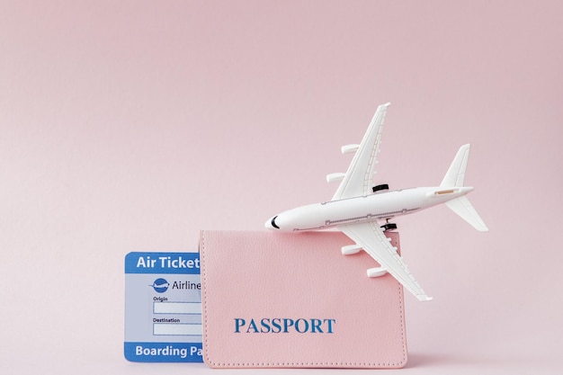 Avião de passaporte e passagem aérea em um fundo rosa Espaço de cópia do conceito de viagem