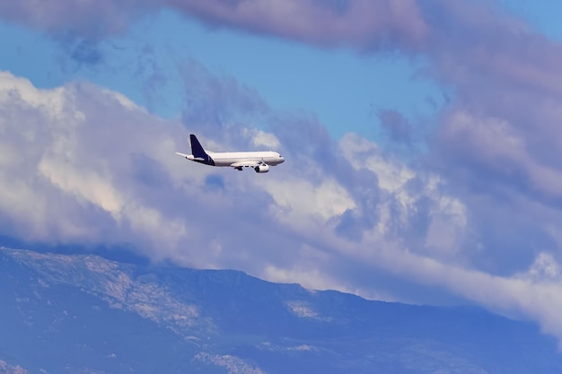 Foto avião genérico voando entre as nuvens acima das altas montanhas