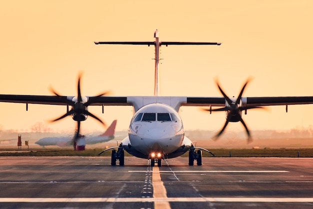 Avião na pista contra o céu durante o pôr do sol