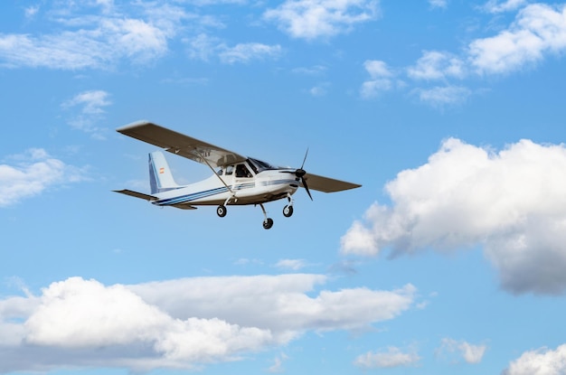 Avião ultraleve monomotor voando no céu azul com nuvens brancas