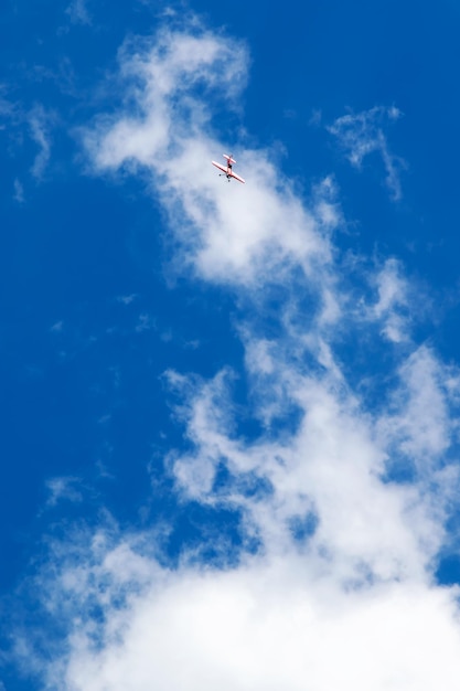 Avião vermelho-branco voando para o céu azul com nuvens