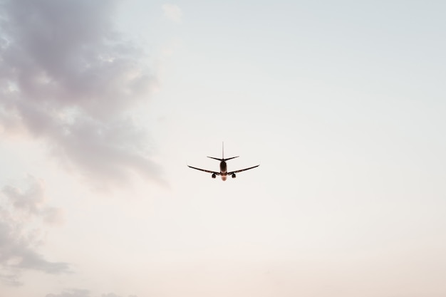 Avião voando no céu ao pôr do sol com nuvens rosa roxas