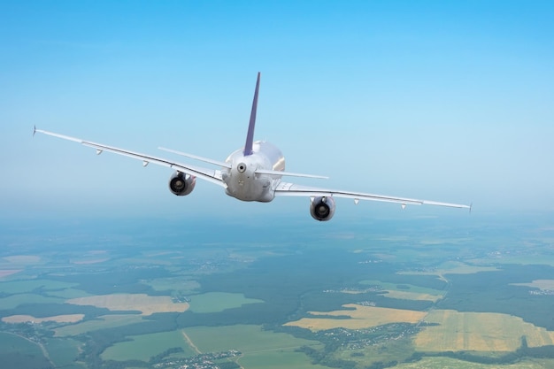 Foto avião voando para longe em um céu claro não muito acima da superfície da terra