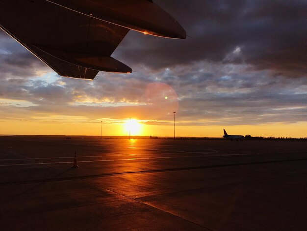 Foto avião voando sobre a pista contra o céu durante o pôr do sol