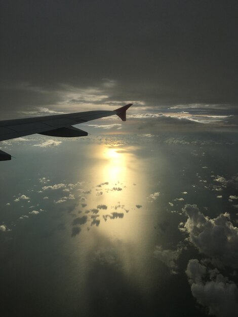 Foto avião voando sobre o mar contra o céu durante o pôr do sol