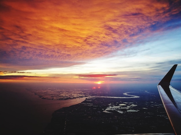Foto avião voando sobre o mar na cidade durante o pôr-do-sol
