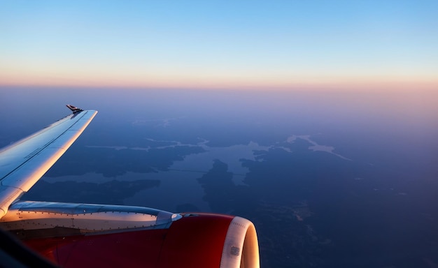 Foto avião voando sobre terras contra o céu durante o pôr do sol