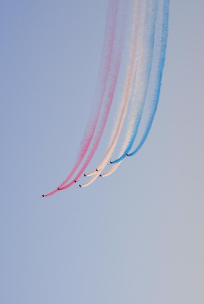 Aviões de combate militares voam em grupo com fumaça no céu azul