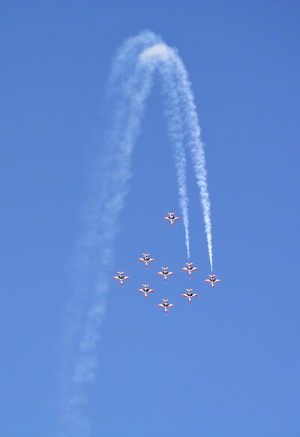 Aviões de combate militares voam em grupo com fumaça no céu azul