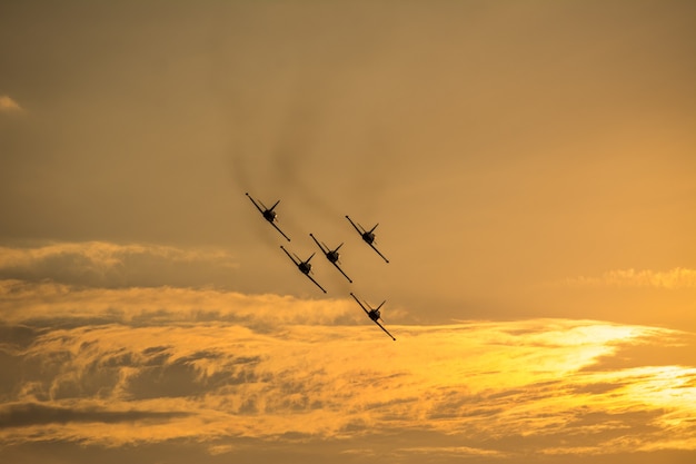 Aviões em formação voando no céu ao pôr do sol