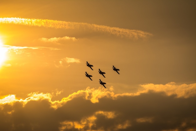 Aviões em formação voando no céu ao pôr do sol