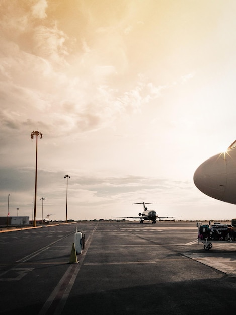Aviões na pista contra o céu durante o pôr do sol