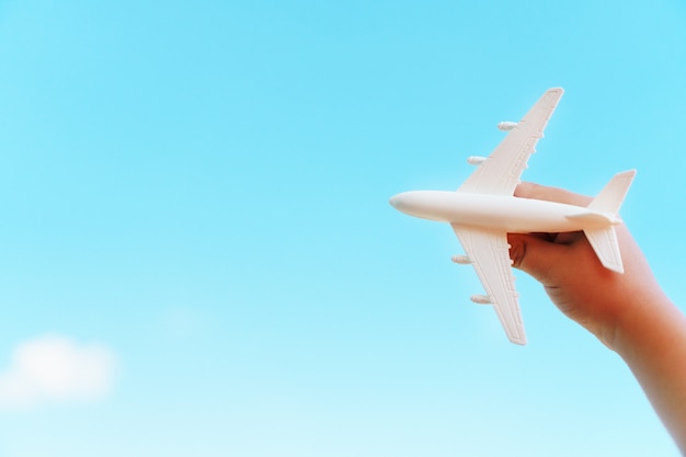 Un avión blanco en la mano de un niño contra un cielo azul