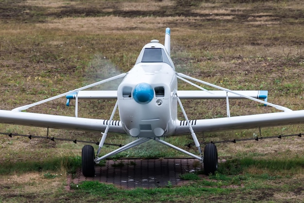 Avión blanco para rociar campos agrícolas en el aeródromo con un motor en marcha