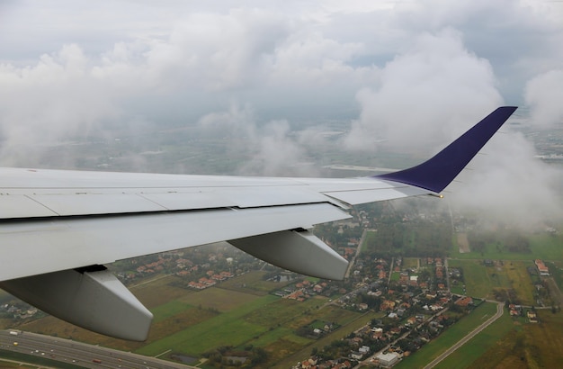 Avión en el cielo sobre campos verdes, el ala es visible a través de la ventana de transporte aéreo.