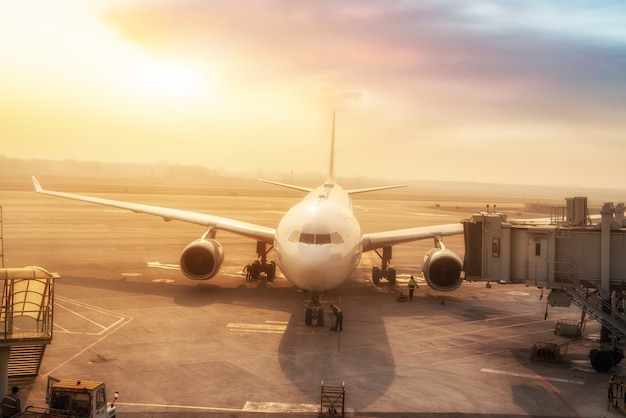 Avión civil en la plataforma del aeropuerto en la puesta de sol