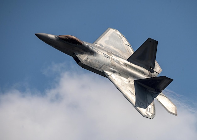 Un avión de combate plateado vuela en el cielo.