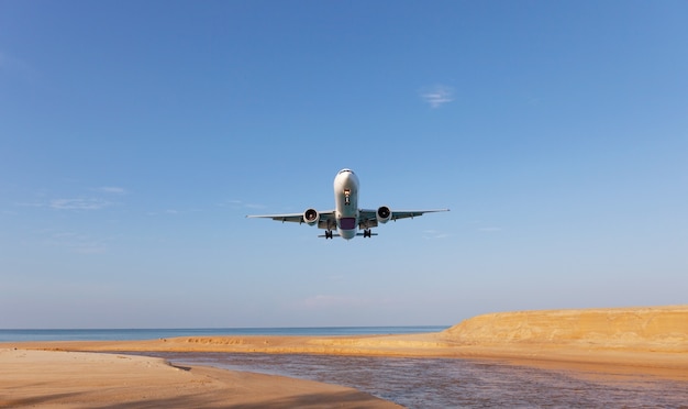 Avión comercial aterrizando sobre el mar en temporada de verano y cielo azul claro sobre hermosos paisajes