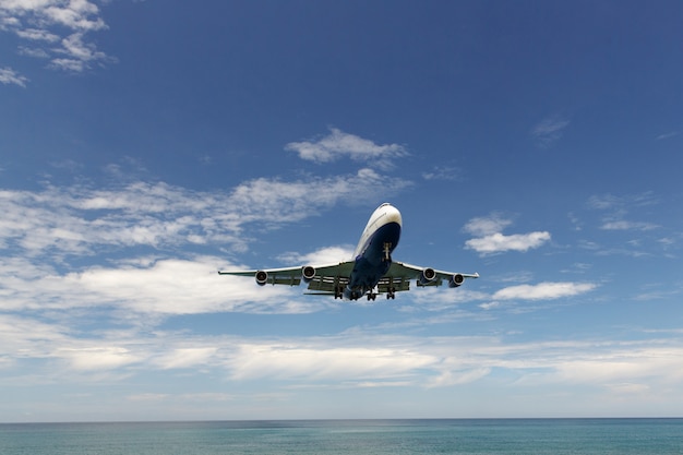 Avión comercial moderno avión volando en el cielo azul sobre el mar