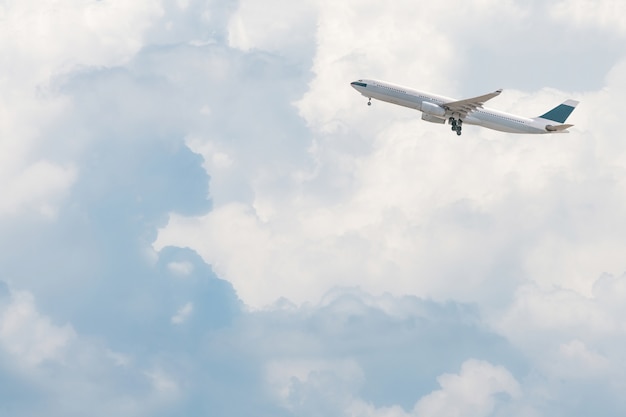 Avión comercial que vuela sobre el cielo azul brillante y las nubes blancas.